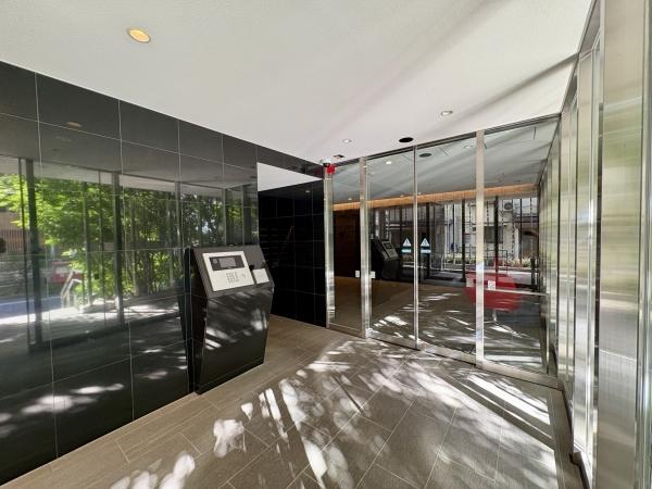 ガラス扉と豊かな植栽が調和する、洗練されたエントランス