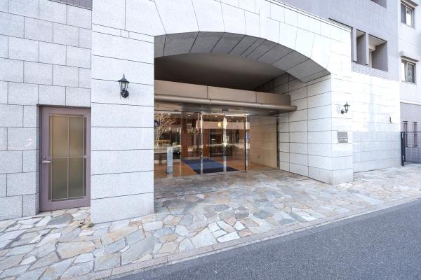 気品あふれるアイアンや素材感を感じる表情が印象的なタイルを用いたマンションエントランス