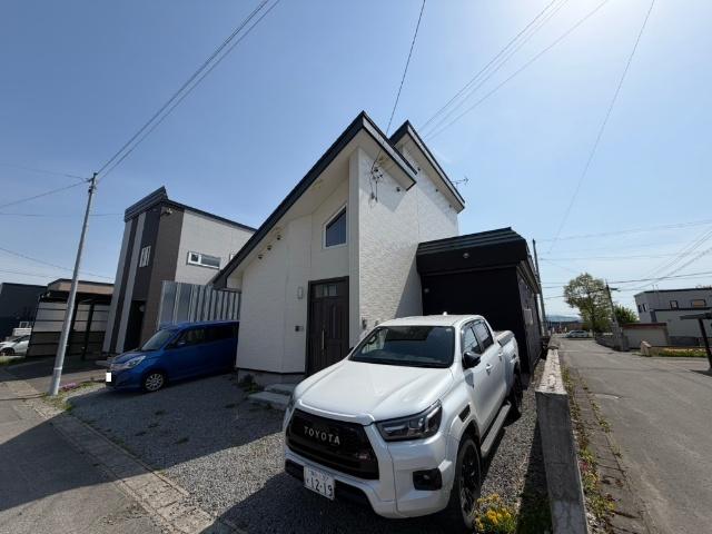 別アングルから見た現地外観。前面道路からの見通しも良く、車の出し入れがしやすい配置です。スタイリッシュな白ベースの壁面が青空に美しく映え、周辺の落ち着いた環境とも調和するモダンな佇まいの住まい。