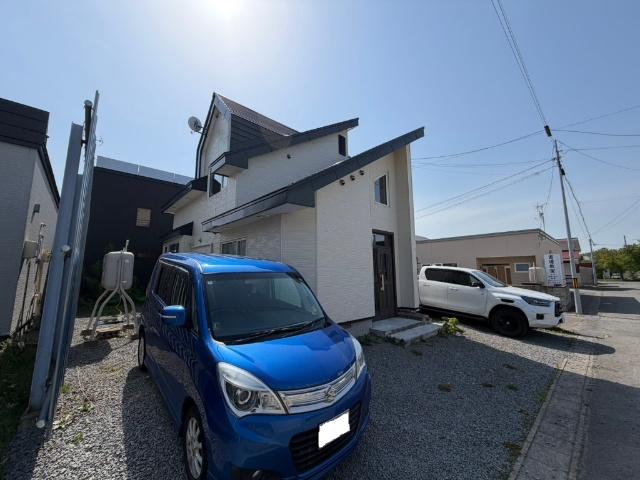 敷地全体の広さが伝わる外観写真。コンパクトカーから大型車まで駐車しやすいスペースがあり、自転車などを置くゆとりも十分にあります。すっきりとした外観デザインは、飽きのこないシンプルな美しさが特徴。