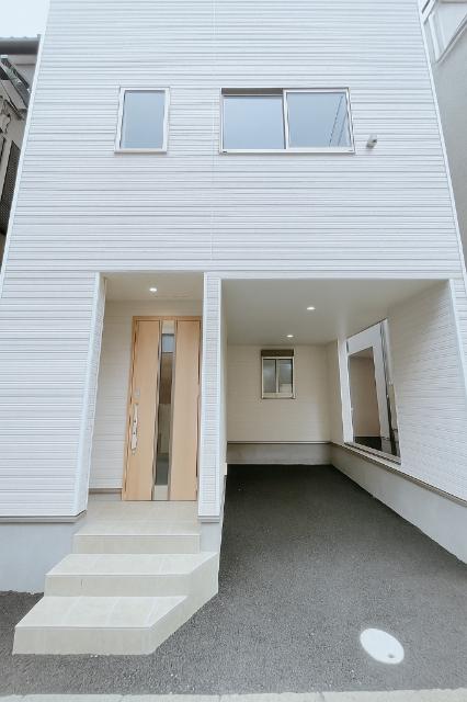 外観はシンプルな建売住宅ですが、駐車場は屋根付きで雨の日も安心です。玄関前にも屋根があり便利ですが、駐車場の間口は少し狭めです。建物を出てすぐが私道なので、歩行者や車の通行には注意が必要です。